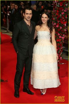 two people standing next to each other on a red carpet with flowers in the background