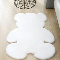 a white teddy bear rug sitting on top of a wooden floor next to a vase