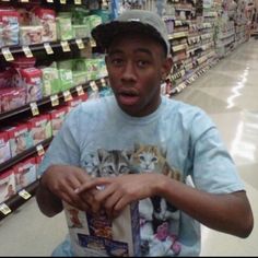 a man in a store holding a bag of cat food and making a surprised face