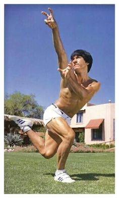 a shirtless man is playing frisbee on the grass in front of a house