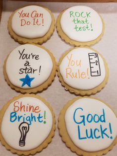 four decorated cookies in a box with writing on them that say you're star, shine bright, good luck, rock that test