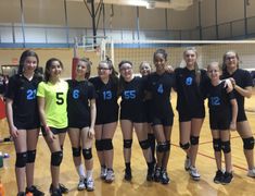 a group of young women standing next to each other in front of a volleyball net