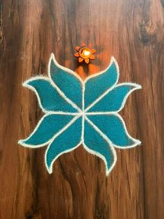 a blue and white flower on top of a wooden table next to a small candle