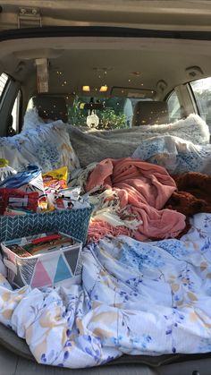 the back of a car filled with blankets and other items, including books and toys