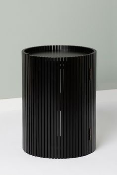 a black round table sitting on top of a white floor next to a gray wall