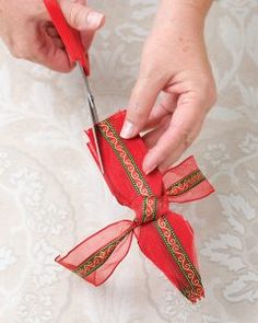 a woman cutting ribbon with scissors on top of a piece of paper that has been folded