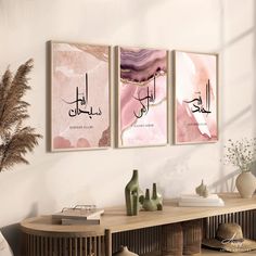 two framed art prints on the wall above a table with vases and plants in front of it