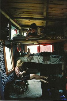 two people sitting on top of bunk beds in a room with wood floors and walls