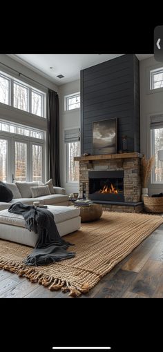 a living room with large windows and a fire place in the middle of the room