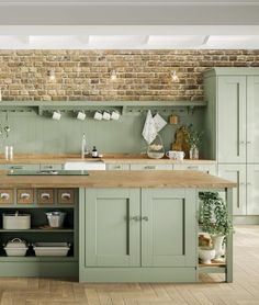 a large kitchen with green cabinets and wooden counter tops, along with an island in the middle