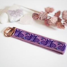 a purple keychain sitting on top of a table next to flowers and rocks