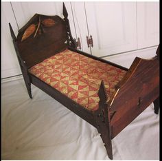 an old wooden bed with red and gold quilt