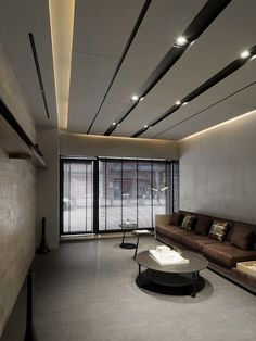 a living room with couches, tables and lamps on the ceiling is lit by recessed lights