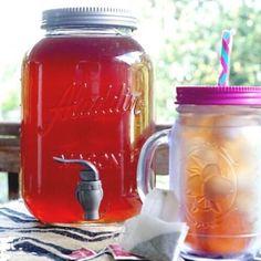 two mason jars filled with liquid sitting on top of a table next to each other