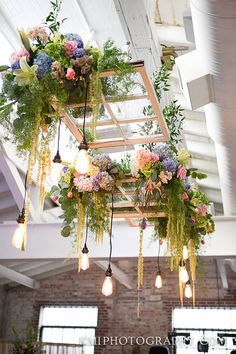 an indoor wedding venue with flowers hanging from the ceiling