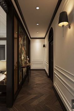 a long hallway with white walls and wood flooring is lit by a black lamp