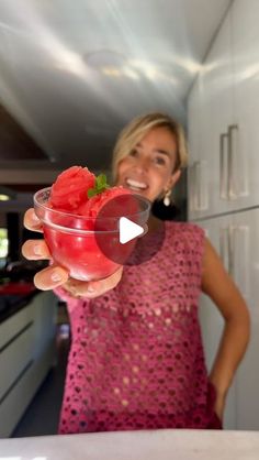 a woman holding up a glass filled with ice cream and watermelon in her hand