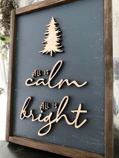 a wooden sign that says all is calm, all is bright with a pine tree on it