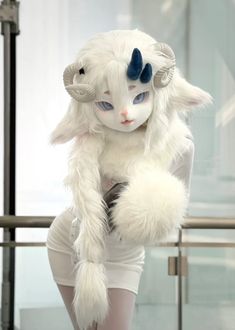 a woman dressed in white with blue eyes and horns