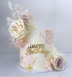 a birthday cake decorated with flowers and the words happy birthday written on it in gold lettering