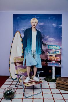 a woman standing in front of a surfboard on top of a chair next to a sign