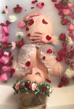 two women laying in a bathtub with rose petals