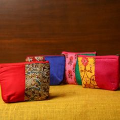 four different colored zippered pouches sitting on top of a yellow cloth covered surface