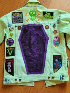 a jacket made out of old clothing with buttons and stickers on the front, sitting on a wooden floor