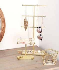 a wooden table topped with gold jewelry and a clock on the wall behind it's stand