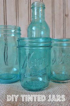 four mason jars are lined up on a burlock tablecloth with the words, diy tinted jars