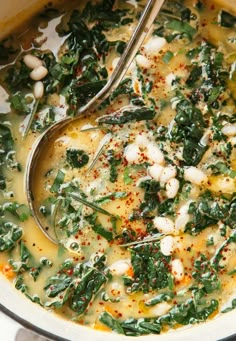 a pot filled with soup and vegetables on top of a stove next to a spoon