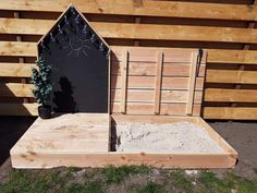 a wooden bed frame with sand in it and a potted plant next to it