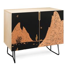 a cabinet with an image of mountains and cactuses painted on the front, along with metal legs