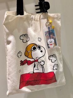 a white bag with a cartoon dog on it and a tag hanging from the handle