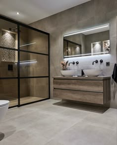 a modern bathroom with two sinks and a large glass door leading to the shower area