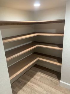 an empty walk in closet with white walls and wooden shelves on the bottom shelf,