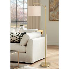 a living room with a white couch and a gold floor lamp next to a window