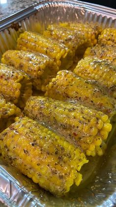 corn on the cob is sitting in a tin foil container with some seasoning