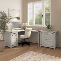 an office with a desk, chair and potted plant on the floor in front of two windows