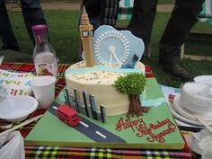 a birthday cake with the london eye in the middle on a table at an outdoor party