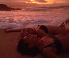 two women laying on the beach at sunset