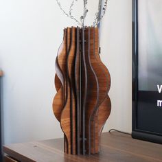 a wooden vase with branches in it on top of a table next to a television