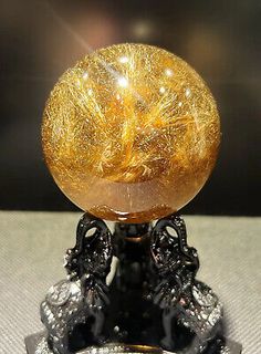 a glass ball sitting on top of a black and white stand with gold foiling