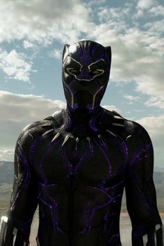 the black panther is standing in front of some clouds and mountains with his hands on his hips