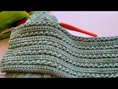 a crocheted bag sitting on top of a table next to a green plant