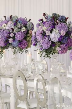 two vases filled with purple and white flowers on top of a dining room table