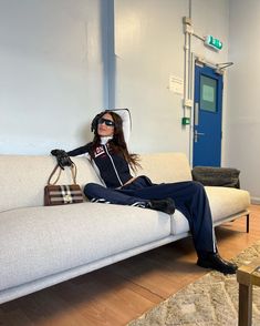 a woman sitting on top of a white couch holding a purse and wearing headphones