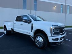 a white pickup truck parked in a parking lot next to a building with large windows