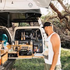 a man standing in front of a van filled with cooking utensils and food