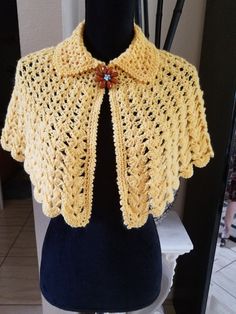 a yellow crocheted shawl on top of a mannequin headdress